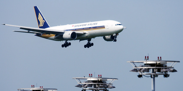 A Singapore Airlines Boeing 777 passenger plane descends past lighting towers at Changi Airport. Photo by Jonathan Drake/Bloomberg News