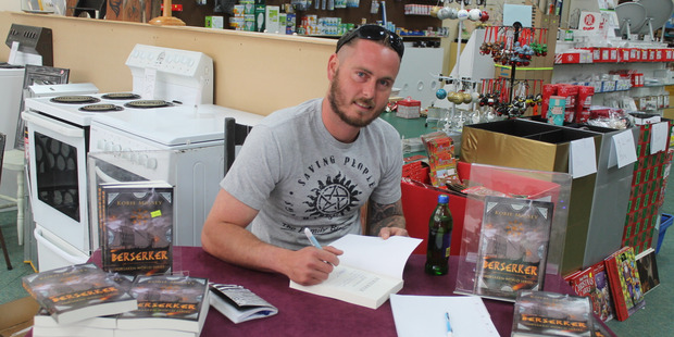 Korie Massey signs his book Berserker in his parent's shop, Derek's Electrical on Saturday November 18.