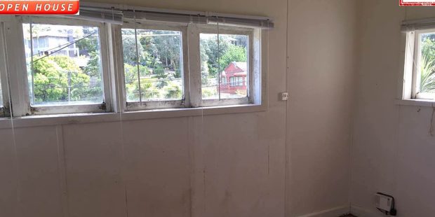 A room inside the Castor Bay property showing mould on the walls and cracked, peeling paint on the window frames. Photo / Trade Me