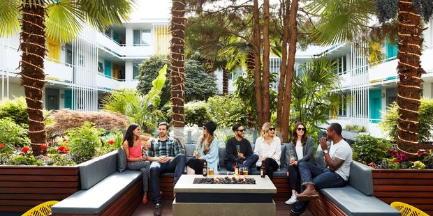 Guests chat in the lush interior garden courtyard, fringed with palms.