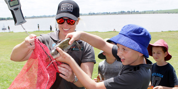 Community DoC ranger Dannika Frost helps Ngahinapouri School student Zanre van der Merwe weigh his catfish caught at Lake Ngāroto.