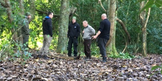 Senior DOC ranger Murray Cleaver (centre right) inspects the tourists' campsite at Whakaipo Bay after they were discovered camping illegally in a recreation reserve area. Photo /Supplied