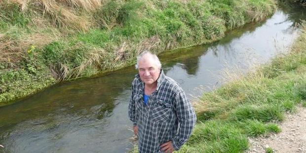 Ray McCrostie stands by the Waituna Stream which runs through his property. Photo / Ken Muir